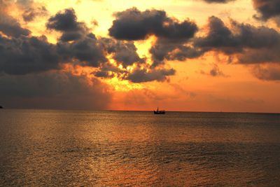 Silhouette boat sailing in sea against dramatic sky