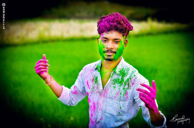 Portrait of young man standing against multi colored umbrella