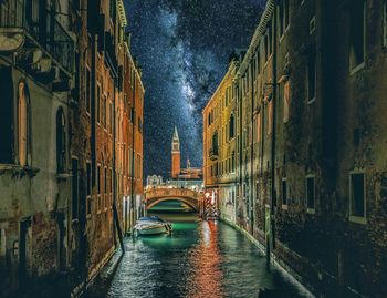 Canal amidst buildings in city during rainy season