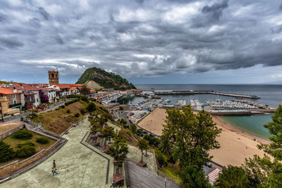 Townscape by sea against cloudy sky