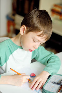 Close-up of boy drawing on book at home