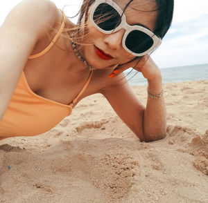 Midsection of woman wearing sunglasses on beach