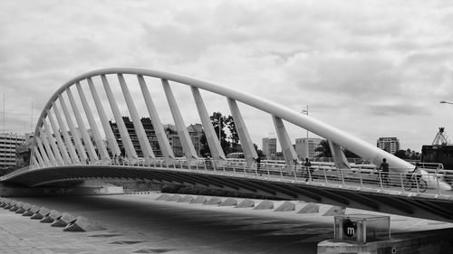 Bridge in city against cloudy sky