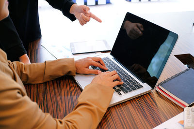 Cropped image of businesswomen using laptop at desk in office