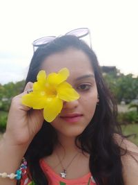 Close-up portrait of woman holding yellow flowers