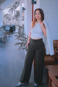 Portrait of young woman standing in front of building