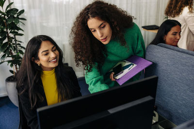 Businesswoman assisting female colleague over computer at office