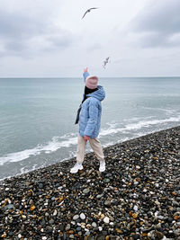 Full length of woman standing at beach against sky