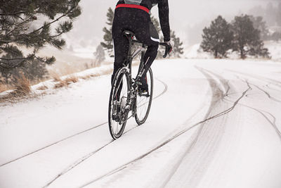 Low section of man cycling on snowy road