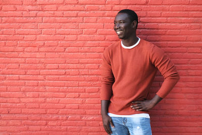 Full length of young man standing against red wall