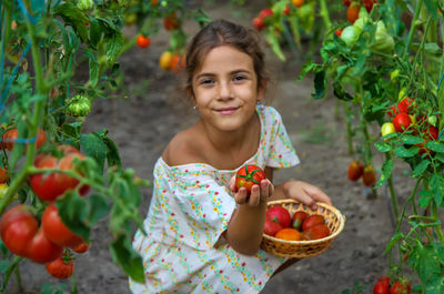 Portrait of smiling girl holding tomatoes in basket