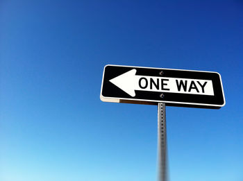 Low angle view of road sign against blue sky