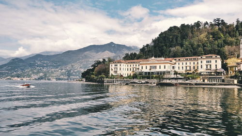 Building by lake against cloudy sky