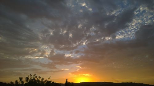 Low angle view of storm clouds over silhouette landscape