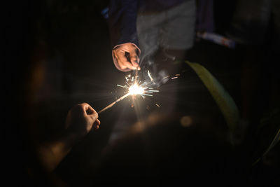 Close-up of woman holding sparkler at night