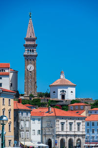 Buildings in city against clear blue sky