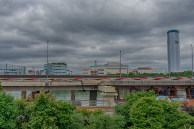 View of bridge and buildings against cloudy sky