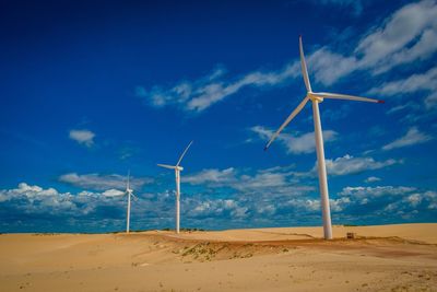 Windmills in desert against sky