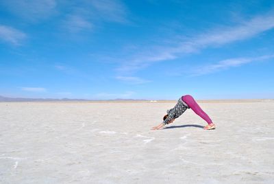 View of woman standing on hands and feet in desert