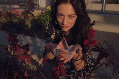 Portrait of woman holding crystal by flowers