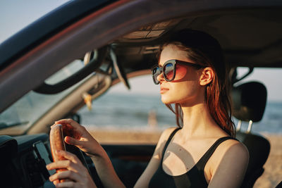 Portrait of young woman wearing sunglasses while sitting in car