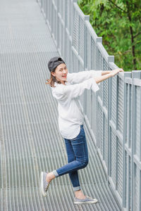 Full length of young woman standing by railing in city