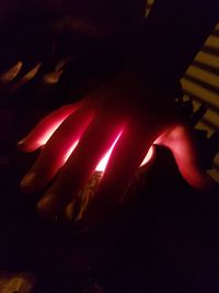 Close-up of hand touching illuminated red lights