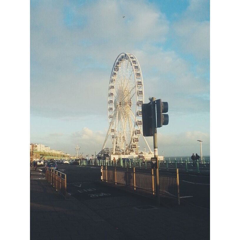 sky, ferris wheel, built structure, transfer print, amusement park, arts culture and entertainment, architecture, amusement park ride, cloud - sky, auto post production filter, building exterior, cloud, city, travel destinations, outdoors, low angle view, metal, water, dusk, sea