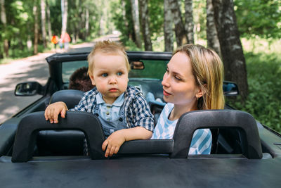 Mom, dad and little son in a convertible car. summer family road trip to nature