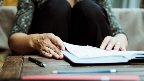 Midsection of woman with book at table