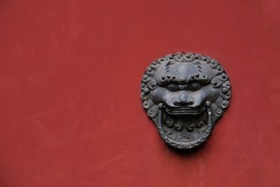 Close-up of a cat statue against red wall
