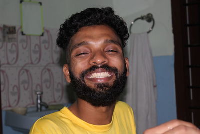 Portrait of smiling young man standing against bathroom