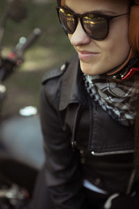 Woman wearing helmet and sunglasses sitting on motorcycle