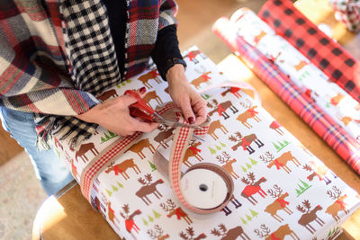 Midsection of woman wrapping gift at home