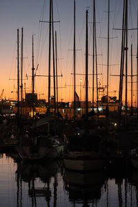 Boats moored at harbor during sunset