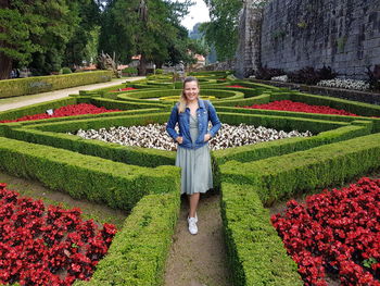 Portrait of smiling woman standing by plants in ornamental garden