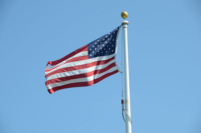 Low angle view of flags against clear blue sky