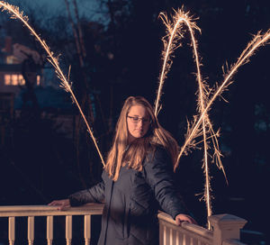 Young woman with arms raised standing at night