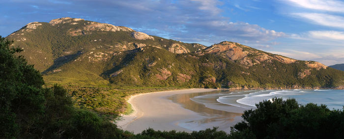 Scenic view of landscape and mountains against sky with beach