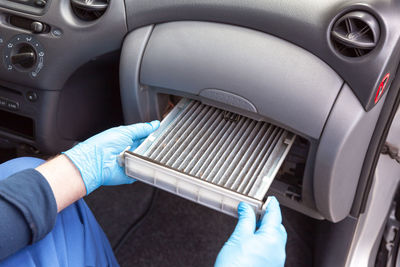 Midsection of man repairing air conditioner in car