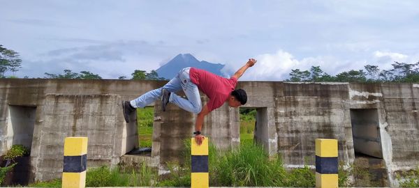 Man balancing on bollard against wall