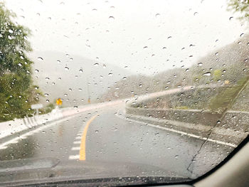 Road seen through wet glass window in rainy season