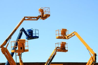 Low angle view of crane against clear blue sky