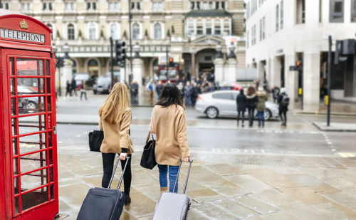Uk, london, two friends exploring the city, arriving with trolley bags