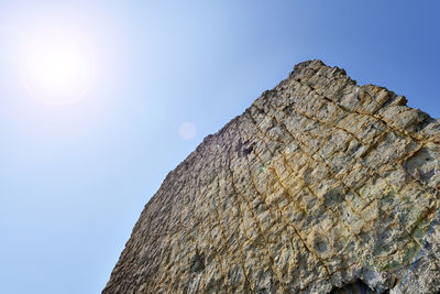 Low angle view of rock against sky on sunny day