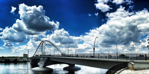 Bridge over river against cloudy sky