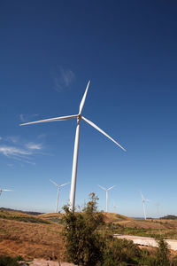 Wind turbines on field against blue sky
