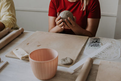 Front view of female potter kneading softly clay on worktop with her hands.