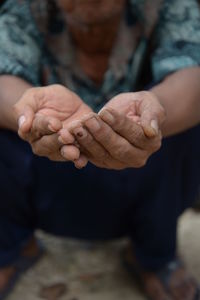 Midsection of man with hands cupped crouching on land