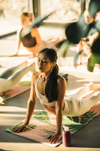 Young woman doing cobra stretch on exercise mat during yoga class at retreat center